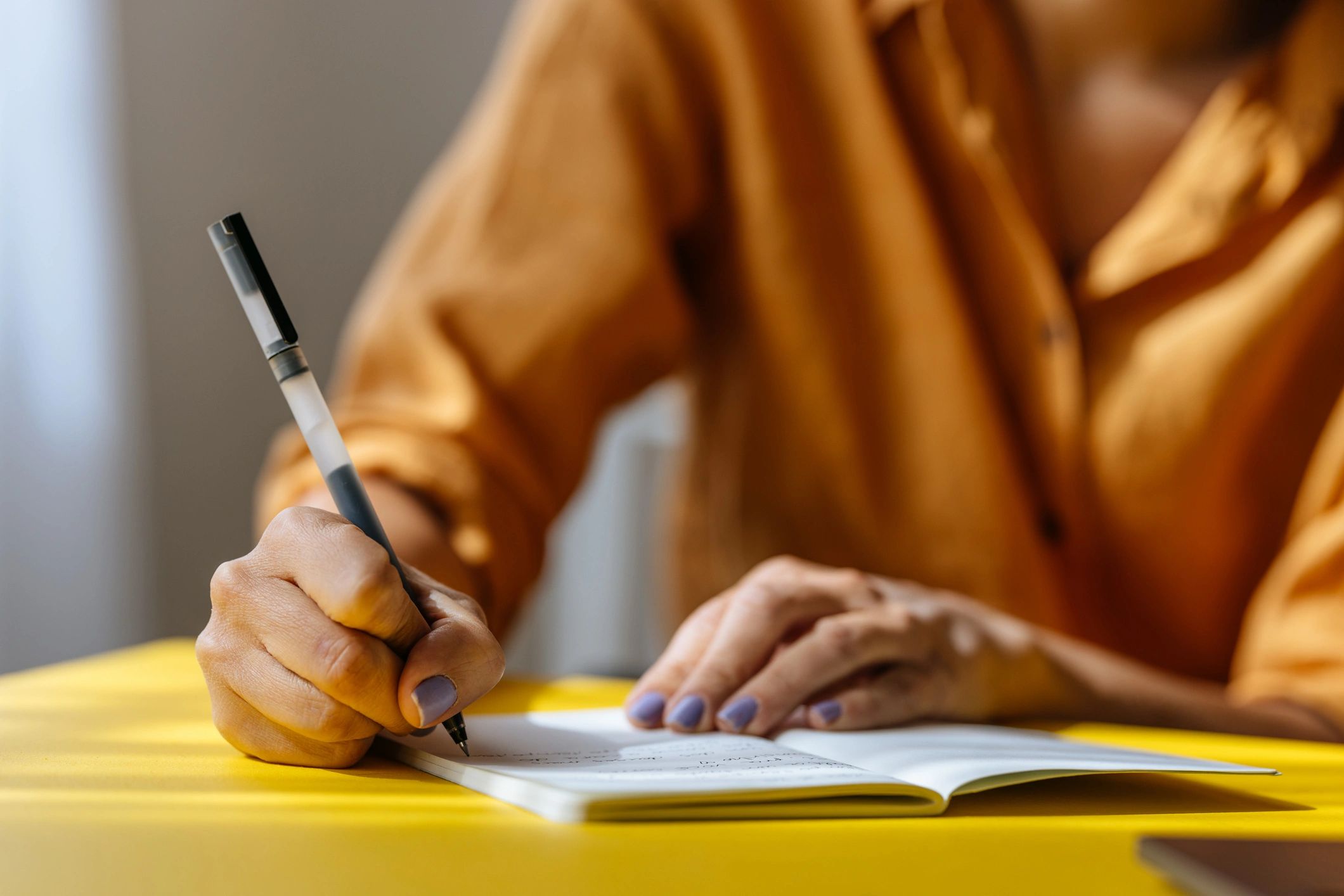 Person taking notes in a notebook while working at a desk